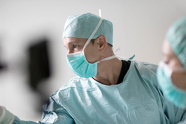 Una persona che indossa un camice chirurgico e una maschera.